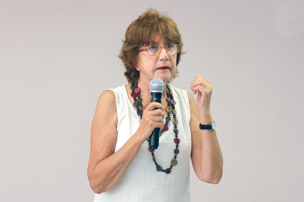 Professora Alinka Lépine-Szily (USP), em pé falando com o microfone na mão.
