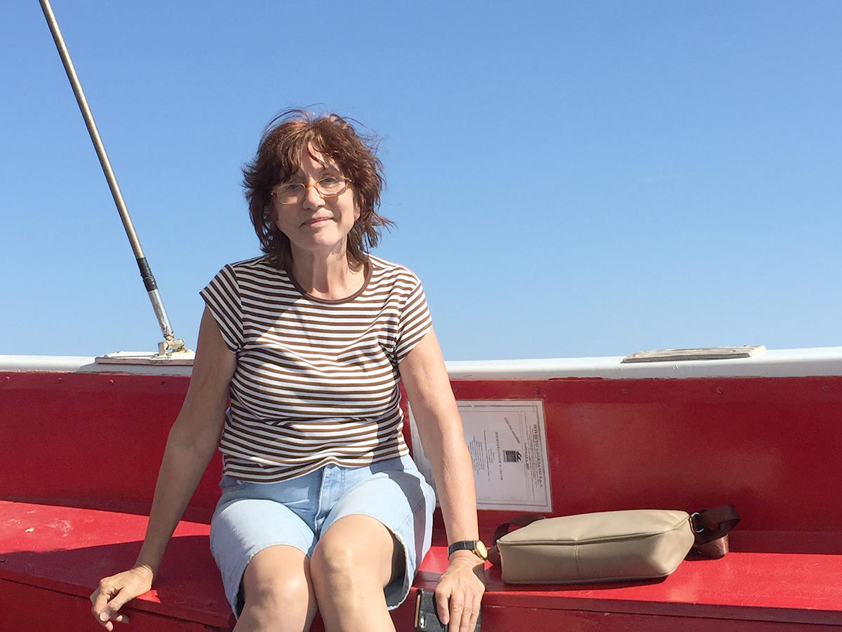 Professora Alinka sentada em uma embarcação, em um dia de sol.